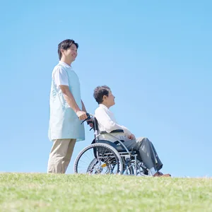 車椅子の女性に付き添う介護職員