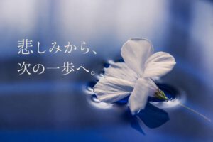 水面に浮かぶ白い花と「悲しみから、次の一歩へ。」の文字。大切な人を亡くした悲しみと希望を表現した海洋散骨のイメージ。